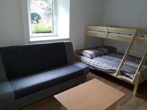 ein Wohnzimmer mit einem Sofa und Etagenbetten in der Unterkunft Apartma Čuvajnica in Hudajužna