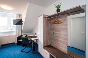 a room with a desk and a table and a chair at Hotel Papenbreer in Verl