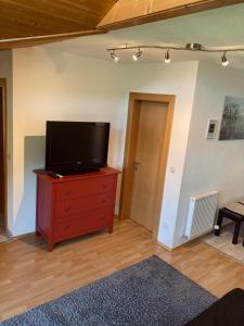 a living room with a flat screen tv on a wooden dresser at Haus Barbara in Ochsengarten