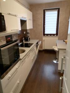 a kitchen with white cabinets and a sink and a window at Joy Apartman in Sovata