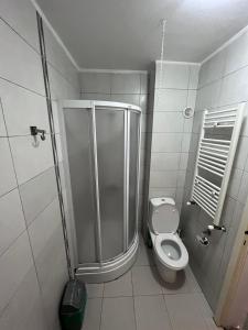 a white bathroom with a shower and a toilet at VORTEX Apartment Skopje in Skopje