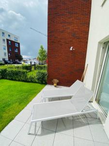 a white bench sitting on a patio next to a brick building at Modern luxurious suite in new private apartment building by the river in Harelbeke