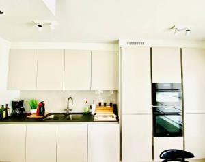 a kitchen with white cabinets and a sink at Luxury apartment "Volmolen" with garden, terrace and free parking in Harelbeke