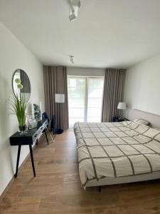 a bedroom with a bed and a table and a mirror at Luxury apartment "Volmolen" with garden, terrace and free parking in Harelbeke