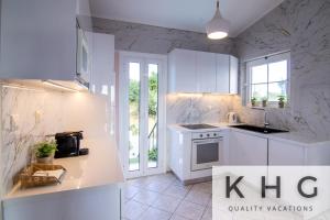 a kitchen with white cabinets and a stove top oven at Villa Aliki with Infinity Pool at Kaminarata Village in Kaminaráta