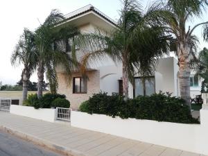 een wit huis met palmbomen ervoor bij Villa Sotmarie in Protaras