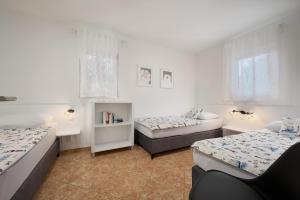 a bedroom with two beds and a desk and two windows at Holiday Park Mandrice in Mandre
