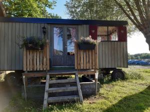 Una casa pequeña con dos cajas de flores. en Pipowagen 'klein Hoonhorst' en Putten