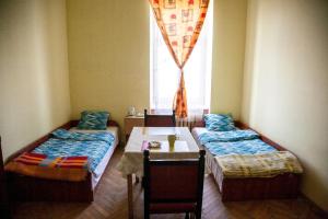 a room with two beds and a table and a window at Pokoje Gościnne in Przemyśl