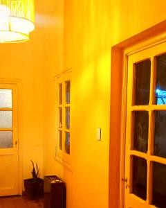 um quarto amarelo com uma porta e uma janela em Hostel LQueen 1 em Salta