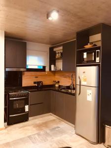 a kitchen with black cabinets and a stainless steel refrigerator at AIKEN con cochera in San Martín de los Andes