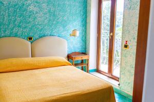 Dormitorio azul con cama y ventana en Grand Hotel Hermitage, en SantʼAgata sui Due Golfi