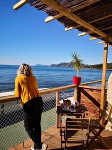 Una mujer parada en un balcón con vistas al agua en Stella Maris, en Hyères