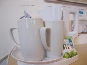three white cups sitting on a plate on a counter at Alhambra Hotel in London