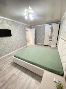 a bedroom with a large bed and a flat screen tv at Vip квартира Центр in Uralsk
