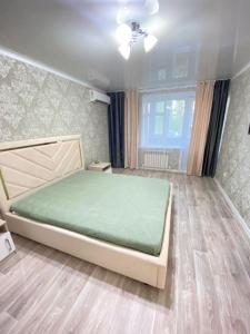 um quarto com uma cama com um colchão verde em Vip квартира Центр em Oral