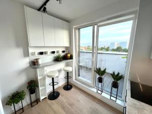 a kitchen with a large window with stools and a counter at Apartament Fredry 2 PREMIUM KLIMA in Kołobrzeg
