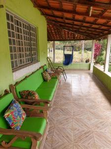 a porch with chairs and a hammock on a house at Pousada Recanto Dos Tucanos in Capitólio