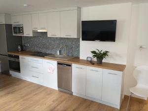 a kitchen with white cabinets and a tv on the wall at Całoroczne Leniuchowo in Ponizie +6 photos