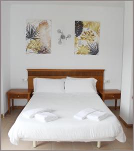 a bedroom with a white bed with three pictures on the wall at Apartamentos Gomila Park in Palma de Mallorca