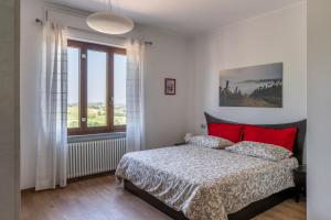 a bedroom with a bed with red pillows and a window at Agriturismo Tenuta La Meridiana in Montegrosso dʼAsti
