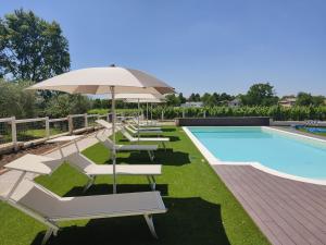 a pool with chairs and an umbrella next to a swimming pool at Al Benandant in Cormòns