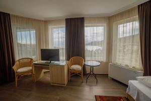 a hotel room with a desk and chairs and windows at Villa Viktor in Topola