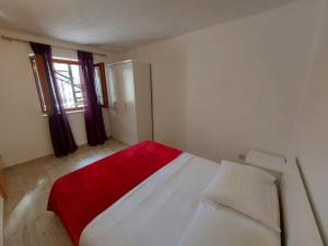 a bedroom with a white bed with a red blanket at Sweet Sea Apartments in Pakoštane