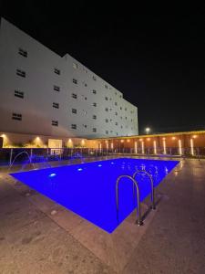 a large blue pool in front of a building at night at Doolv Hotel in Hail