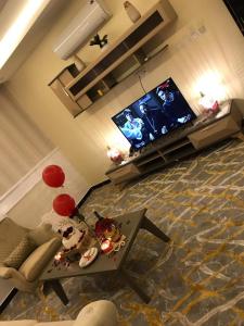 un salon avec une télévision et une table dans l'établissement فندق رذاذ, à Al Kharj