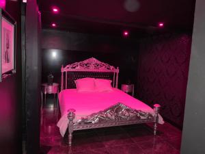 La Suite Marylin, Loft de 90m2 avec Sauna et Jacuzzi في ريوم: غرفة نوم مع سرير وردي مع وسائد وردية