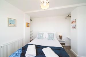 a white bedroom with a bed and a chandelier at The Beach Boathouse in Carnoustie