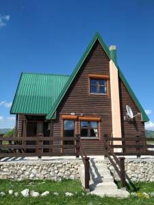 een houten huis met een groen dak en een bank bij Mountain Soul Rest in Žabljak