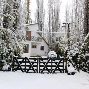 a house with a fence in the snow at Los Abedules Bungalow in Malargüe