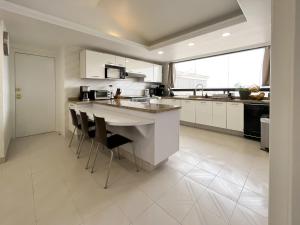 a kitchen with white cabinets and a island with bar stools at Air Lux in Mexico City