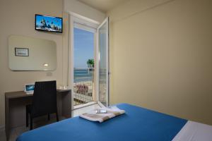 a bedroom with a bed and a desk and a window at Hotel Excelsior in Gabicce Mare