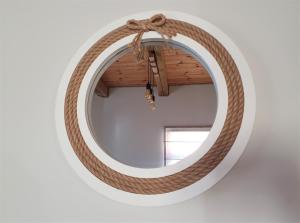 a round rattan mirror with a bow on a wall at KK Apartment in Ventspils