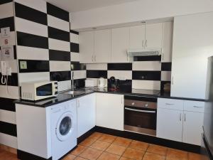 a kitchen with a black and white checkered wall at Apartamento Carvoeiro in Armaes