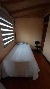 a bedroom with a white bed and a window at Cabaña Punto Punahue in Choshuenco