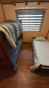 a bedroom with two twin beds and a window at Cabaña Punto Punahue in Choshuenco