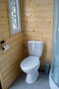 a bathroom with a white toilet in a wooden wall at Beczki Pod Lasem in Trzemeśnia