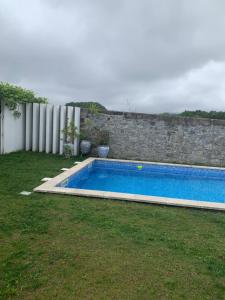 a swimming pool in a yard next to a stone wall at Casa das Uveiras in Paços de Ferreira