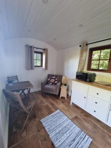 a living room with a table and a chair and a desk at Shepherds hut surrounded by fields and the Jurassic coast in Bridport