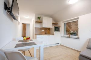 a kitchen with white cabinets and a table and chairs at Na-Ture Apartments in Zgornje Gorje
