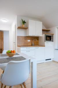 a kitchen with white cabinets and a table and chairs at Na-Ture Apartments in Zgornje Gorje