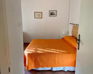 ein Schlafzimmer mit einem Bett mit einer orangefarbenen Decke in der Unterkunft Casa Marinella al confine fra Basilicata e Puglia in Bernalda