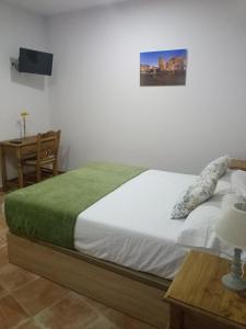 una camera da letto con un letto con una coperta verde e un tavolo di casa rural el Realengo a Las Casas