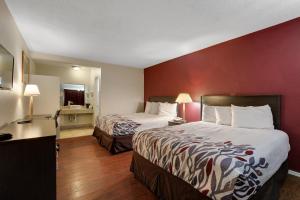 a hotel room with two beds and a red wall at Red Roof Inn Needles in Needles