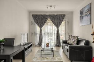 un soggiorno con divano e tavolo di V&S Apartments - Immaculate Luxury Apartment in Fourways, Johannesburg a Fourways
