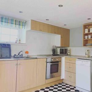 a kitchen with wooden cabinets and a checkered floor at Trewithian Farm Cottage in Bodmin